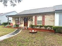 Charming single-story home with a brick facade, covered porch, and well-maintained front yard at 35118 Whispering Oaks Blvd, Dade City, FL 33523