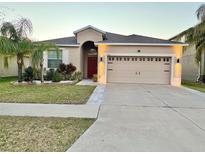 Charming single-story home featuring a well-manicured lawn, a two-car garage, and tropical landscaping at 924 Peregrine Hill Pl, Ruskin, FL 33570