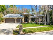 Charming single-story home with a three-car garage, manicured lawn, and beautiful landscaping at 3137 Valemoor Dr, Palm Harbor, FL 34685