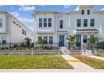 Charming two-story home with a well-manicured lawn, black fence, and a vibrant blue front door at 4717 W Mccoy St # 9, Tampa, FL 33616