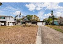 View of house with an attached one car garage on a large grassy lot and mature landscaping at 8001 Orient Ne Way, St Petersburg, FL 33702
