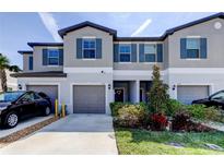 Charming townhome featuring a gray exterior, blue shutters, and well-maintained landscaping at 8294 Corner Pine Way, New Port Richey, FL 34655