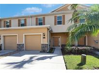 Charming two-story townhome with attached garage, beautiful shutters, and tropical landscaping at 8421 Pine River Rd, Tampa, FL 33637