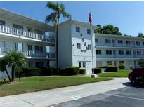 Well-maintained exterior of a condo building featuring a manicured lawn and mature palm trees at 8525 111Th St # 210, Seminole, FL 33772