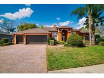 Inviting home featuring a three car garage, brick paver driveway, and well maintained landscaping at 17104 Tiffany Lake Pl, Lutz, FL 33549