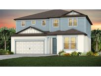 Charming two-story home showcasing a light blue and white color scheme, paired with a two-car garage and inviting front lawn at 37195 Clinch Cir, Zephyrhills, FL 33540