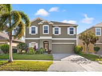 Charming two-story home with a well-manicured lawn, complemented by a lush palm tree and beautiful landscaping at 707 Fern Leaf Dr, Ruskin, FL 33570