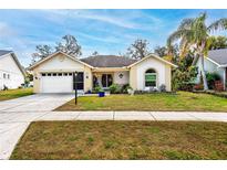 Charming home featuring an attached garage and covered entry way with a manicured lawn and landscaped garden at 4614 Sandpointe Dr, New Port Richey, FL 34655