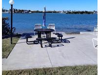 Waterfront picnic area featuring a table, benches, umbrella and chairs along a scenic body of water at 12760 Indian Rocks Rd # 1066, Largo, FL 33774