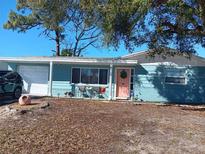 Charming single-story home featuring a pastel exterior, a well-manicured lawn, and a welcoming front porch at 4111 Moog Rd, Holiday, FL 34691