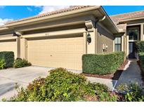 Beige garage door featuring the house number and manicured landscaping in front at 4813 Michelle Ln, Palm Harbor, FL 34684