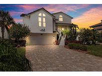 Charming two-story home featuring a brick paved driveway, lush landscaping, and inviting curb appeal at 5241 West Shore Dr, New Port Richey, FL 34652