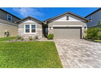 Charming single-story home with stone accents, a two-car garage, and manicured landscaping at 7096 Heron Walk Ln, Wesley Chapel, FL 33545