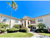 Inviting condo exterior featuring well-manicured landscaping and a grand entrance with a palm tree at 7900 Hardwick Dr # 813, New Port Richey, FL 34653