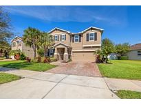 A two-story home with neutral exterior, paver driveway, well-maintained lawn, and mature landscaping at 12225 Lake Blvd, New Port Richey, FL 34655