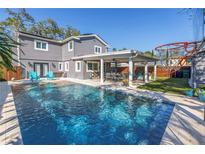 Inviting backyard oasis featuring a large swimming pool, covered patio with seating, and well-maintained lawn area at 4514 W Beachway Dr, Tampa, FL 33609