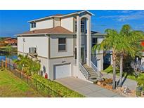 A beautiful two-story home features a garage, landscaped yard with palm trees, and access to a waterfront view at 5100 Cedarbrook, Hernando Beach, FL 34607