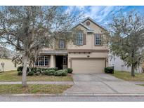 Two-story home features a well-maintained lawn and a beige stucco facade at 10909 Observatory Way, Tampa, FL 33647