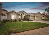 Charming home with a well-manicured lawn, colorful flower beds, and a three-car garage at 1204 Blackrush Dr, Tarpon Springs, FL 34689