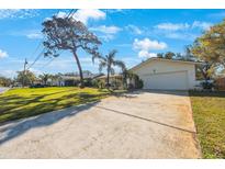 Charming single-story home featuring a spacious driveway, lush lawn, and mature trees at 3370 Harbor Lake Dr, Largo, FL 33770