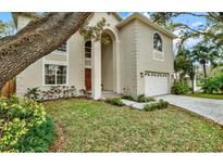 Charming home boasts an arched entryway, two-car garage, and lush landscaping, creating inviting curb appeal at 407 S West Shore Blvd, Tampa, FL 33609