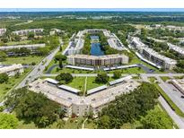 An aerial view of a condo community featuring a central lake, green spaces, and multiple residential buildings at 5750 80Th N St # A106, St Petersburg, FL 33709