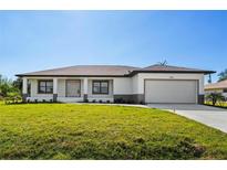 Charming single-story home with a well-manicured lawn, attached garage, and neutral-toned exterior paint at 7235 Peacock Ln, Englewood, FL 34224