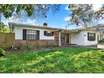 Charming single story home with brick accents, dark shutters, mature landscaping, and a cozy front porch seating area at 3112 S Julia Cir, Tampa, FL 33629