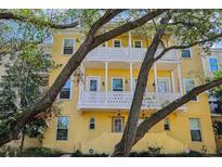 Charming yellow townhome with double balconies and shade trees at 958 Sombra St, Tampa, FL 33619