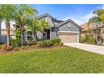 Charming single-Gathering home featuring a manicured lawn, complemented by mature palm trees, and a two-car garage at 1435 Montgomery Bell Rd, Wesley Chapel, FL 33543
