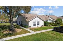 Charming home with a manicured lawn, mature trees, and a welcoming walkway leading to the entrance at 2345 Bentley Dr, Palm Harbor, FL 34684