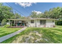 Charming single-story home with a covered porch, lush lawn, and decorative accents creating a welcoming curb appeal at 2708 De Montmollin Rd, Plant City, FL 33565