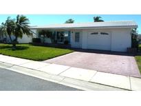 Charming single-story home with a well-manicured lawn, palm trees, and a brick driveway leading to a one-car garage at 3472 100Th N Ter, Pinellas Park, FL 33782