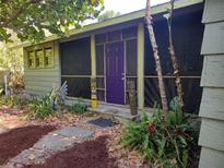 Charming home with a screened-in porch, vibrant purple door, and unique tiki decorations at 1044 Virginia Dr, Sarasota, FL 34234