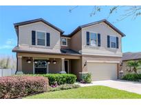 Charming two-story home featuring a manicured lawn, flowering plants, and a welcoming front porch at 2208 Landside Dr, Valrico, FL 33594