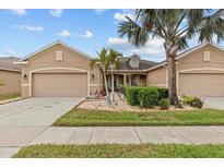 Charming single-story home featuring a well-manicured lawn, mature palm trees, and an attached two-car garage at 2240 Parrot Fish Dr, Holiday, FL 34691