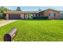 Charming one-story brick home featuring a lush front lawn, manicured bushes, and an attached garage at 2484 Roberta St, Largo, FL 33771
