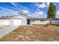 Charming single-story home with a blue door, freshly painted gray exterior, and driveway at 3333 Chauncy Rd, Holiday, FL 34691