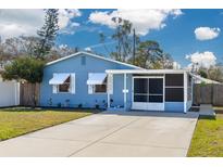 Charming blue home featuring a screened-in porch and a well-maintained front yard at 358 51St N Ave, St Petersburg, FL 33703