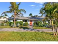 Charming single-story home with lush landscaping, vibrant plants and a welcoming orange front door at 1500 Carson Ne Cir, St Petersburg, FL 33703