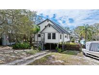Stilt house with a driveway, boat, and a well-maintained yard and landscaping at 3327 Pineview Dr, Holiday, FL 34691