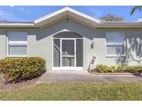 Inviting front entrance with an arched door, well-maintained landscaping, and a charming, light green exterior at 1205 Huntington Greens Dr, Sun City Center, FL 33573