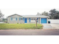 Charming single-story home featuring a stone facade, bright blue shutters and door, and a well-manicured front lawn at 302 N Lauber Way, Tampa, FL 33609