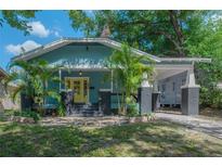 Charming home featuring a light blue exterior with a yellow front door and a welcoming covered porch at 5603 N Taliaferro Ave, Tampa, FL 33604