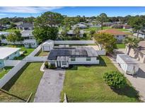 Overhead view of the white home with solar panels, surrounded by a white fence and lush landscaping at 1054 W Baffin Dr, Venice, FL 34293