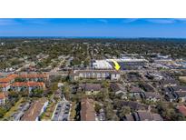 Wide aerial view of a condo complex and surrounding area with trees, roads, and nearby shopping center at 1216 S Missouri Ave # 225, Clearwater, FL 33756
