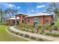 Exterior facade of home showcasing arched windows, professional landscaping, and decorative house numbers at 2307 7Th Sw St, Ruskin, FL 33570