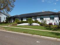 Charming white brick home featuring lush landscaping, solar panels, and a well-manicured lawn at 2709 Fairway View Dr, Valrico, FL 33596