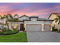 Stunning home with a well-manicured lawn, lush landscaping, and a paver driveway leading to a spacious three-car garage at 809 Seascape Pl, Sarasota, FL 34240