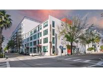 Modern condo building featuring white accents, a red door, lots of windows, and manicured landscaping at 101 N 12Th St # 306, Tampa, FL 33602
